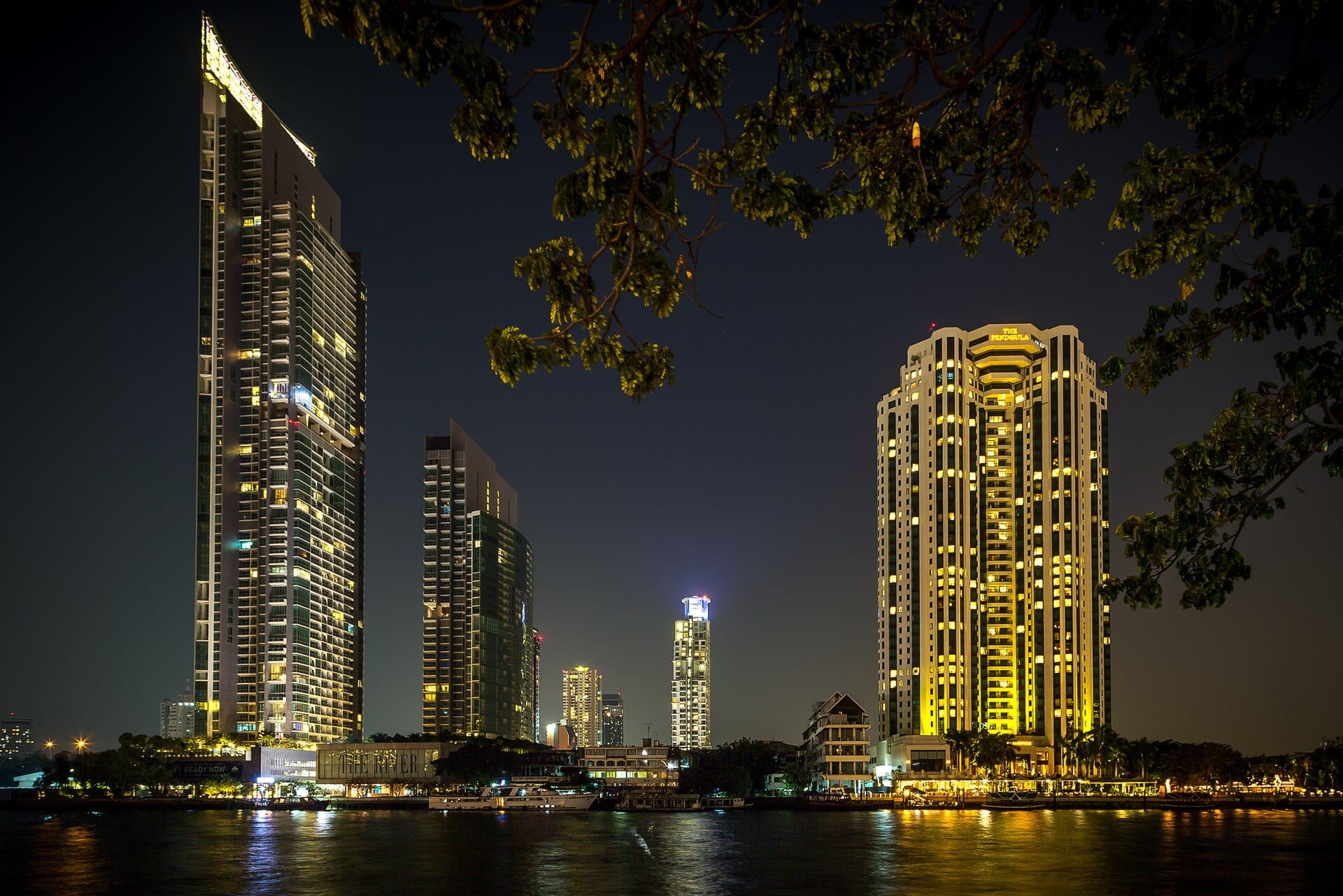 The Chao Phraya river in Bangkok at night, with lit buildings along the bank.