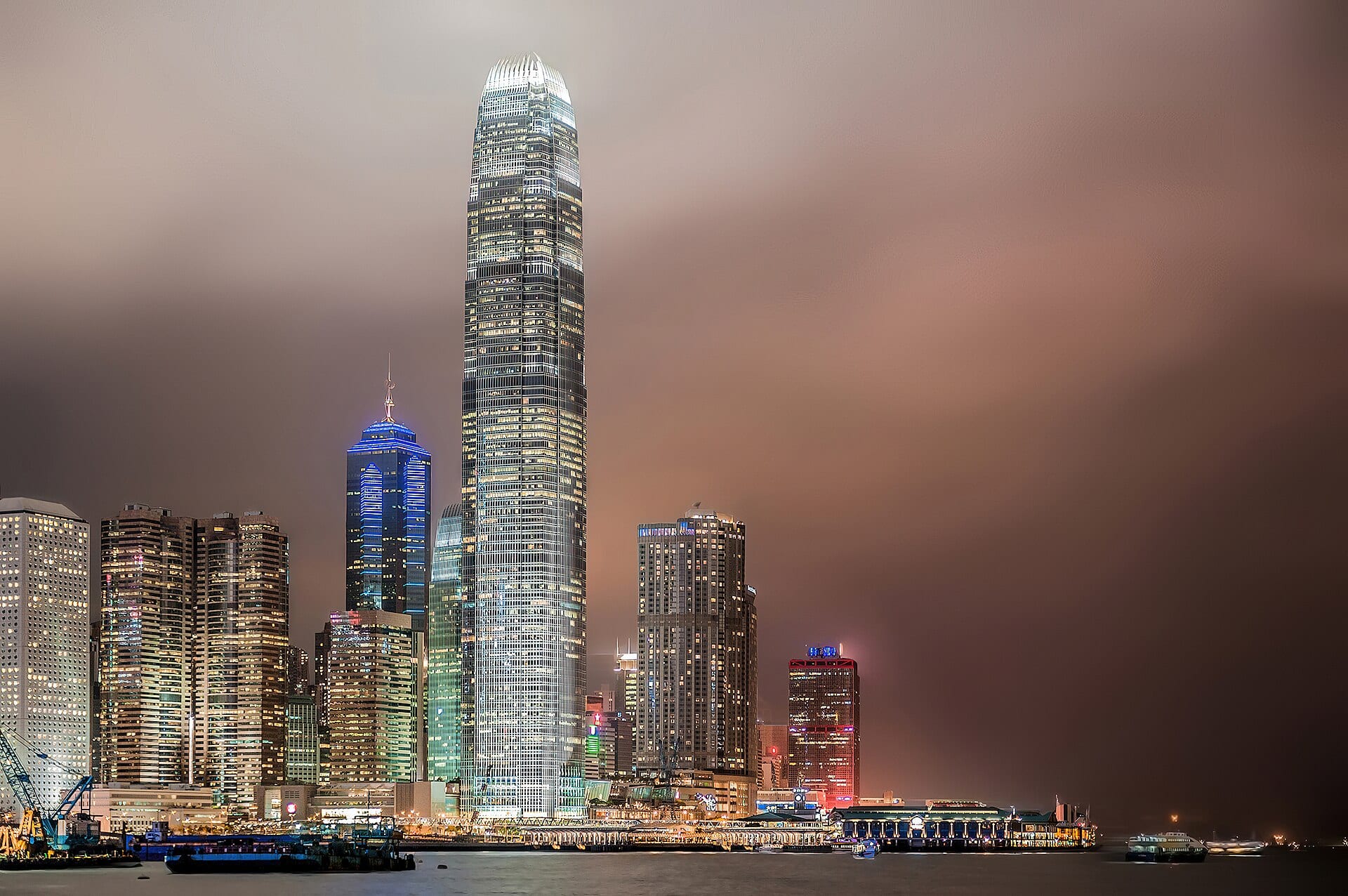 Hong Kong skyscrapers lit at night, seen across the harbour.