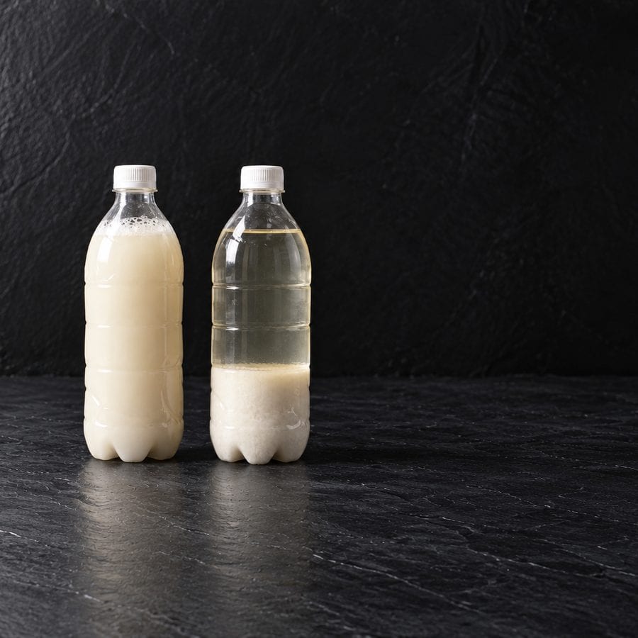 Two bottles of makgeolli side by side, the left one shaken and opaque, the right one settled clear with sediment at the bottom.